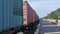 a goods train running and a container lorry driving down the road.