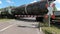 Goods train with tanker passes a single level crossing at a road junction