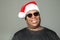 Goofy African American man wearing a Santa Claus hat against a solid background