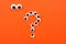Googly eyes. Strange persons with mad eyes look at some crazy toy eyes on orange background. In the shape of question