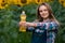 Gorgeous, adorable, energetic, female farmer holding a bottle of sunflower oil in the middle of a beautiful sunflower field