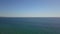 Gorgeous aerial footage of the vast blue rippling ocean water with waves rolling into the beach with a gorgeous clear blue sky