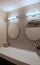 Gorgeous bathroom with round mirrors, patterned wall and soft lighting overhead