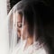 Gorgeous beautiful bride in silk robe under veil posing at window in soft light. Happy stylish Bride with perfect makeup smiling.