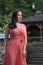 Gorgeous biracial woman poses wearing pink dress in garden