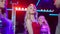 Gorgeous blond woman with blue eyes in red dress dancing with group of friends in night club lights. Smiling charming