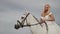 Gorgeous blonde in a white wedding dress riding a horse