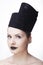 Gorgeous blonde woman model with blue eyes and black lipstick wearing big stylish designer black unique hat/ headpiece