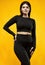 Gorgeous body positive Latin woman in a black suit on a yellow background