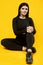 Gorgeous body positive Latin woman in a black suit on a yellow background