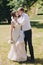 Gorgeous bride in amazing gown and stylish groom kissing and laughing in sunny park. Beautiful happy wedding couple enjoying time