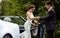 Gorgeous bride with fashion makeup and hairstyle in a luxury wedding dress with handsome groom near white cabriolet car