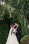 Gorgeous bride and stylish groom gently hugging on background of