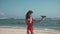 Gorgeous brunette in red swimsuit on the beach launching drone. Cute girl catching drone, exploring the area. Drone