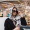 Gorgeous business young beautiful woman with vintage silk scarf on head in sunglasses is resting in cafe. Fashionable elegant girl