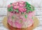 Gorgeous cake covered in roses made of butter cream icing on white wooden background