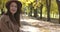 Gorgeous Caucasian lady in elegant hat spinning in the autumn park. Beautiful European woman with pleasant smile and