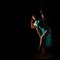 Gorgeous dancer in night club. woman in a long turquoise dress with a slit on a dark background. free space for