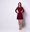 Gorgeous dark-haired young woman standing hands on hips in elegant dark-red sequin dress with long sleeves and nude stilettos