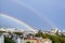 Gorgeous double rainbow over city. A double rainbow appeared against gray stormy sky over residential area of the city