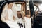 gorgeous elegant bride posing in stylish retro black car, sitting inside in saloon holding bouquet of callas. luxury wedding in v