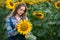 Gorgeous, energetic, female farmer cultivating from one of the sunflowers from the big green field