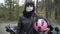 Gorgeous female biker in Covid-19 face mask and leather jacket standing with pink helmet and looking at camera. Portrait