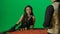Gorgeous female in studio on chroma key green screen. Appealing woman in dress and man croupier at the blackjack poker