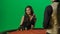 Gorgeous female in studio on chroma key green screen. Appealing woman in dress and man croupier at the blackjack poker