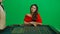 Gorgeous female in studio on chroma key green screen. Appealing woman in red dress and male croupier at the roulette