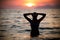 Gorgeous fit woman silhouette swimming in sunset.Free happy woman enjoying sunset. Beautiful woman in water embracing the gol