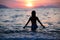 Gorgeous fit woman silhouette swimming in sunset.Free happy woman enjoying sunset. Beautiful woman in water embracing the gol