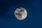 Gorgeous full moon in a dark blue night sky gets covered by soft wispy dark clouds