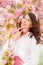 gorgeous gentle caucasian woman under blooming pink sakura tree