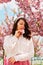 Gorgeous gentle caucasian woman under blooming pink sakura tree