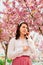 gorgeous gentle caucasian woman under blooming pink sakura tree