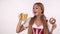 Gorgeous German waitress in dirndl drinking beer, holding delicious pretzel