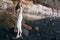 Gorgeous girl in a long white dress on the ocean at the beach. The long-haired girl is inherited by nature, mountains, stones, the