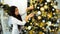 Gorgeous Girl in New Year`s Mood Finishes Decorating Christmas Tree in Bright Bedroom.