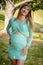 A Gorgeous Glowing Pregnant Woman Poses In An Outdoor Environment