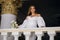 A gorgeous and incredibly beautiful bride in a white dress stands indoors and holds a wedding bouquet