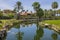 Gorgeous landscape view of hotel area with green golf fields and pond infront of hotel buildings. Palm trees and blue sky.