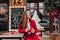 Gorgeous long-haired female model sitting in cafe in spring day. Outdoor portrait of glamorous lady in red jacket