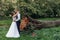 Gorgeous, merry, glad, young married couple, man dancing, embracing bride near tree stem on wedding celebration in park
