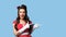 Gorgeous millennial pinup woman in retro style dress pointing aside at empty space on blue background, banner design
