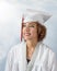 Gorgeous mixed race young lady with curly brown hair in a white cap and gown with red and white tassel
