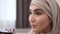 Gorgeous muslim woman doing makeup professionally. Brush eyelashes with mascara. Wearing beige headscarf. White wall on