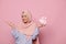 Gorgeous Muslim woman in pink hijab, holding happy present in heart shaped gift box, smiling at camera, pink background