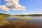 Gorgeous nature landscape on a summer day. Green paint and lawn, mirror water surface and blue sky with white clouds.