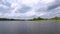 Gorgeous nature landscape on a summer day. Green plants, water surface and blue sky with snow white clouds.